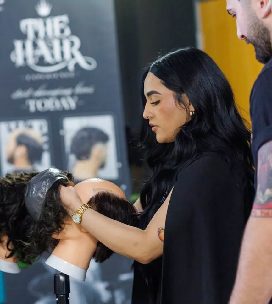 A stylist at The Hair Experience working a hair unit